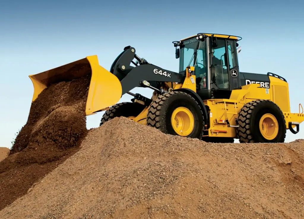 Pá carregadeira John Deere despeja terra em canteiro de obra