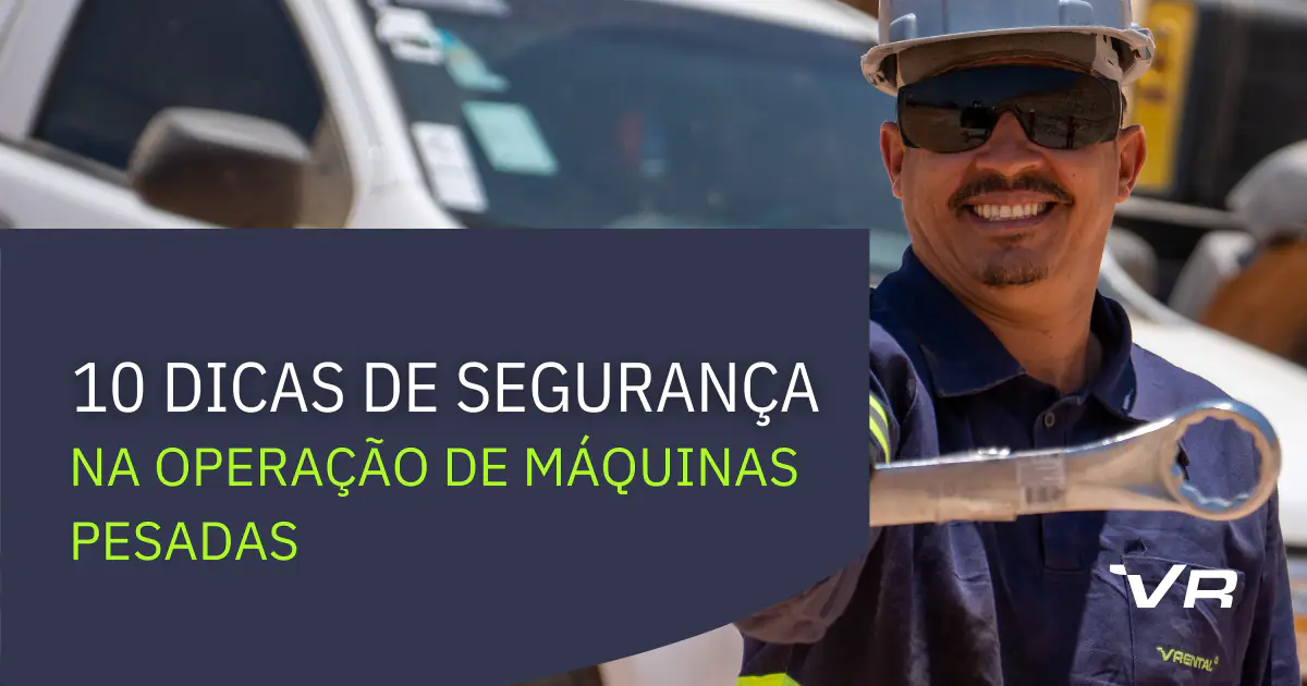 Foto de um mecânico sorrindo, com o braço estendido mostrando uma chave combinada. Em um box azul, o título "I10 dicas de segurança na operação de máquinas pesadas". Ao lado, o ícone da VRental em branco.